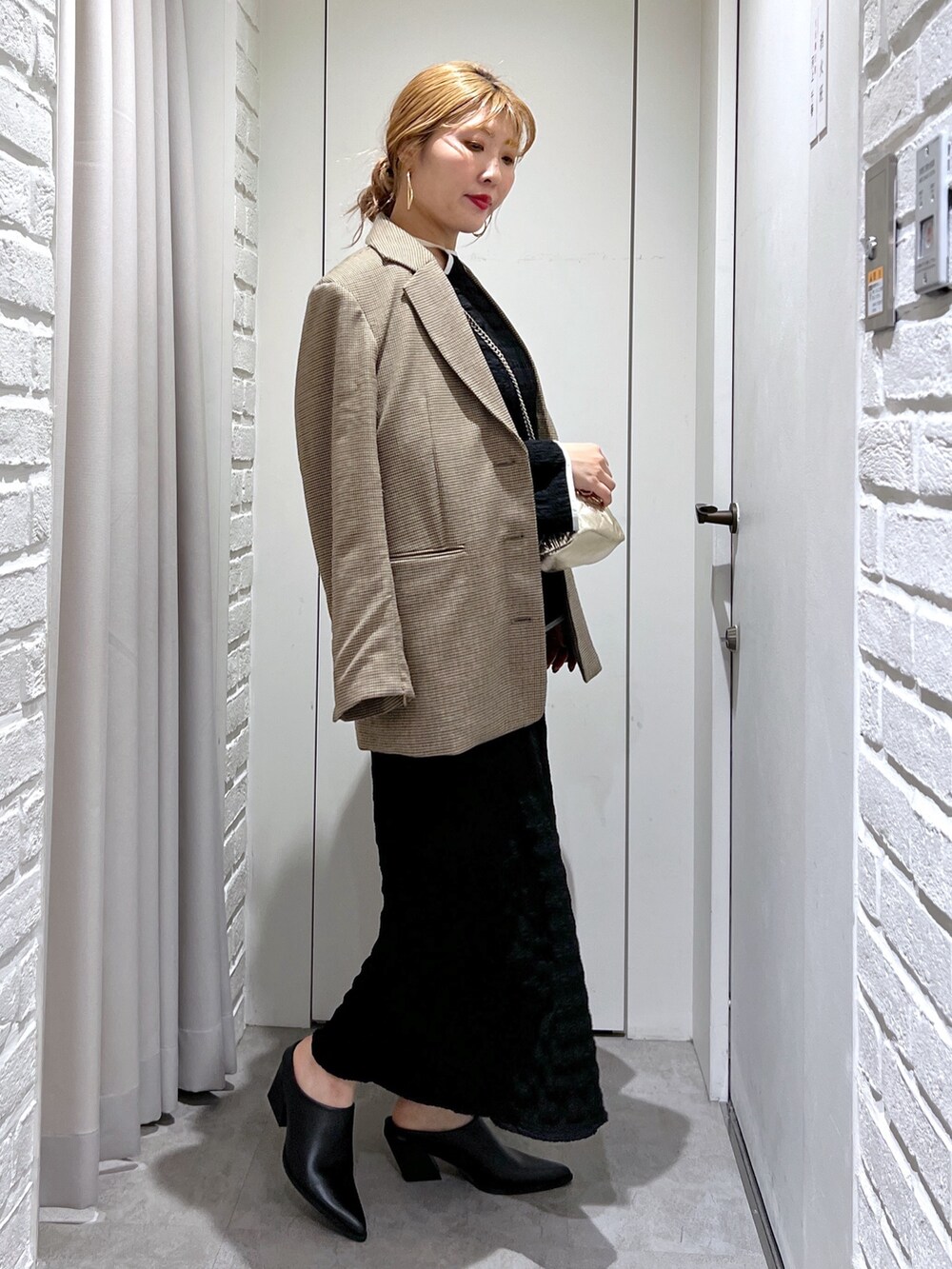 ブラック系のワンピース、ブラック系のパンプス、ゴールド系のショルダーバッグを着用したレディースの春コーディネートの2枚目の写真