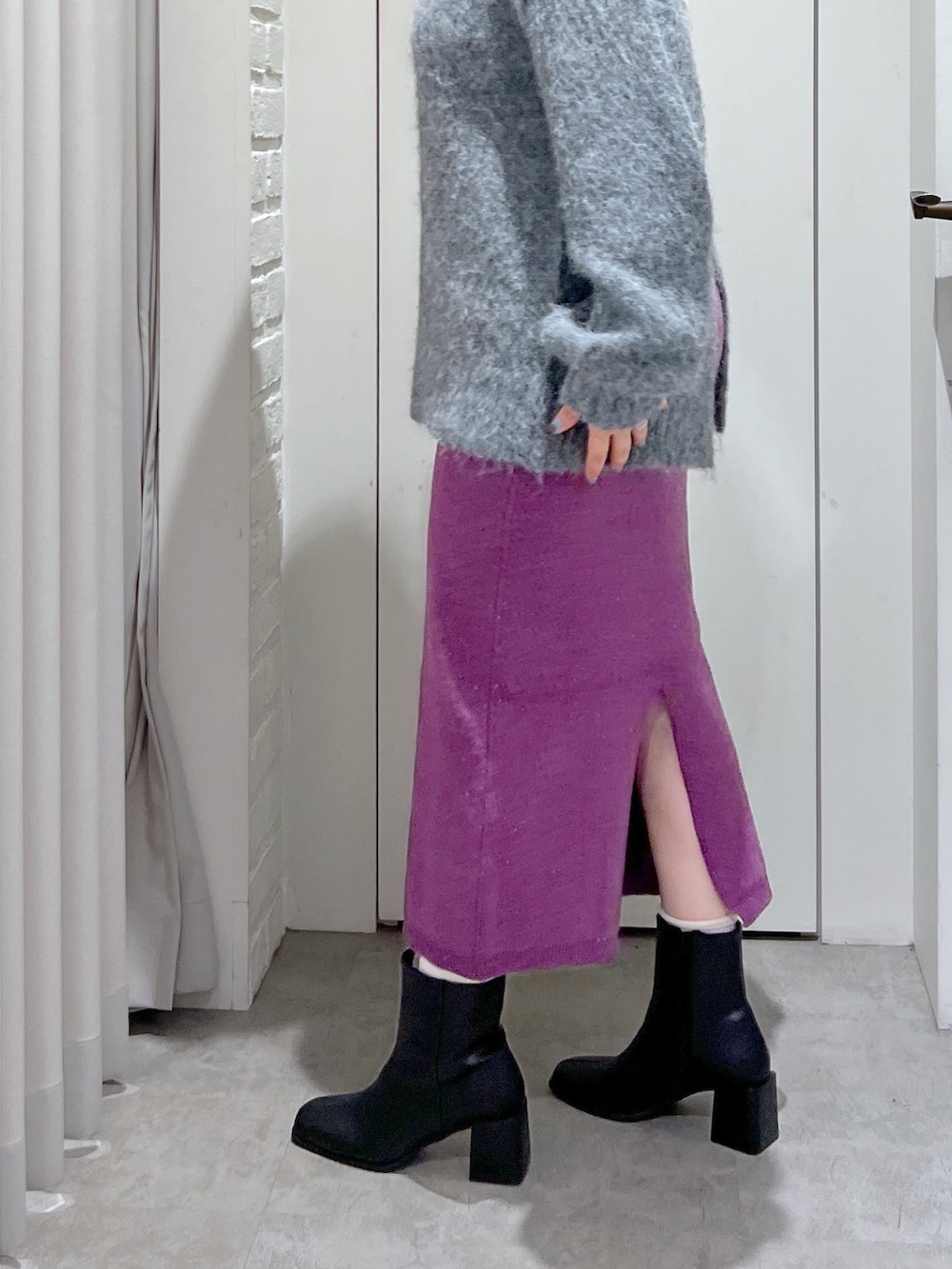 パープル系のスカート、グレー系のニット/セーター、ブラック系のブーツを着用したレディースの冬コーディネートの5枚目の写真