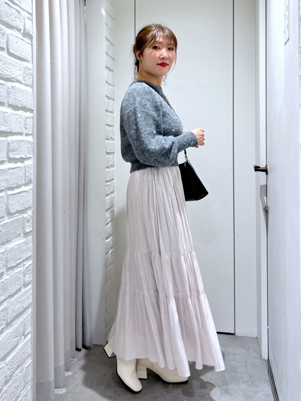 ホワイト系のスカート、グレー系のニット/セーター、ブラック系のショルダーバッグを着用したレディースの冬コーディネートの3枚目の写真