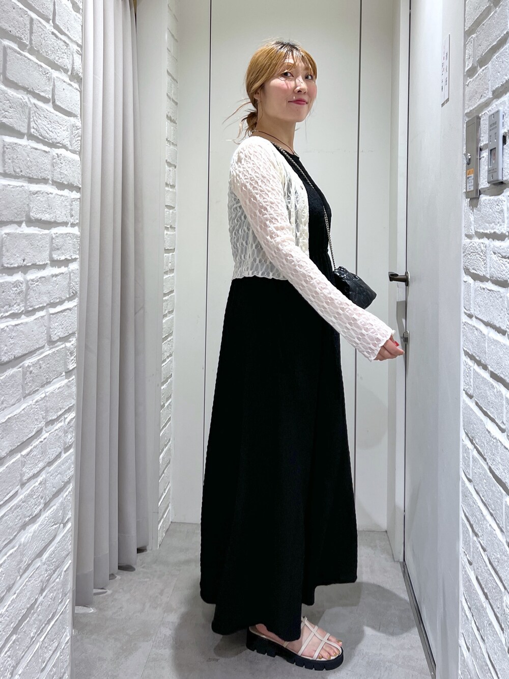 ブラック系のワンピース、ホワイト系のカーディガン/ボレロ、ホワイト系のサンダルを着用したレディースの夏コーディネートの2枚目の写真