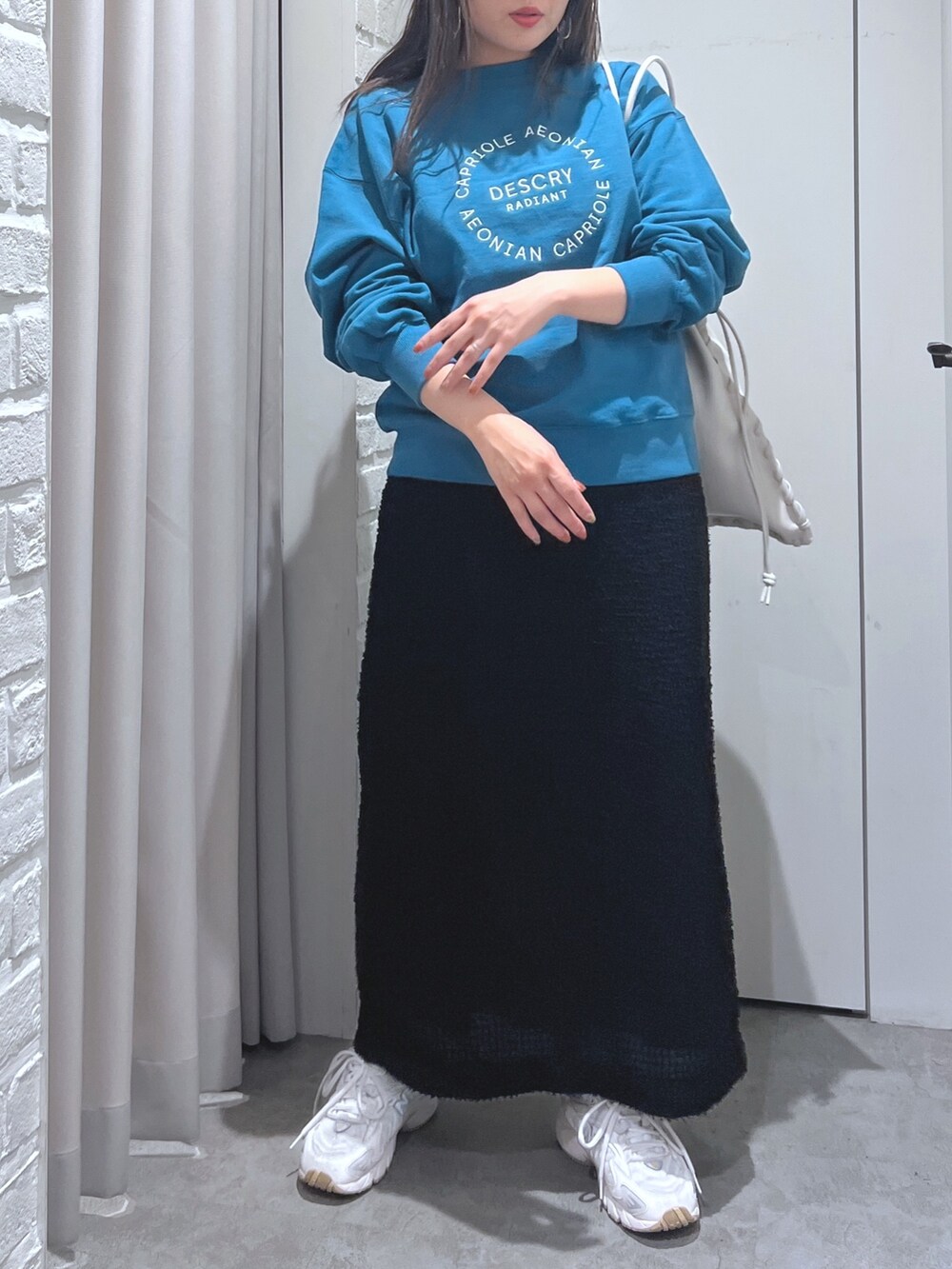 ブラック系のスカート、グリーン系のスウェット、ホワイト系のハンドバッグを着用したレディースの秋コーディネートの3枚目の写真