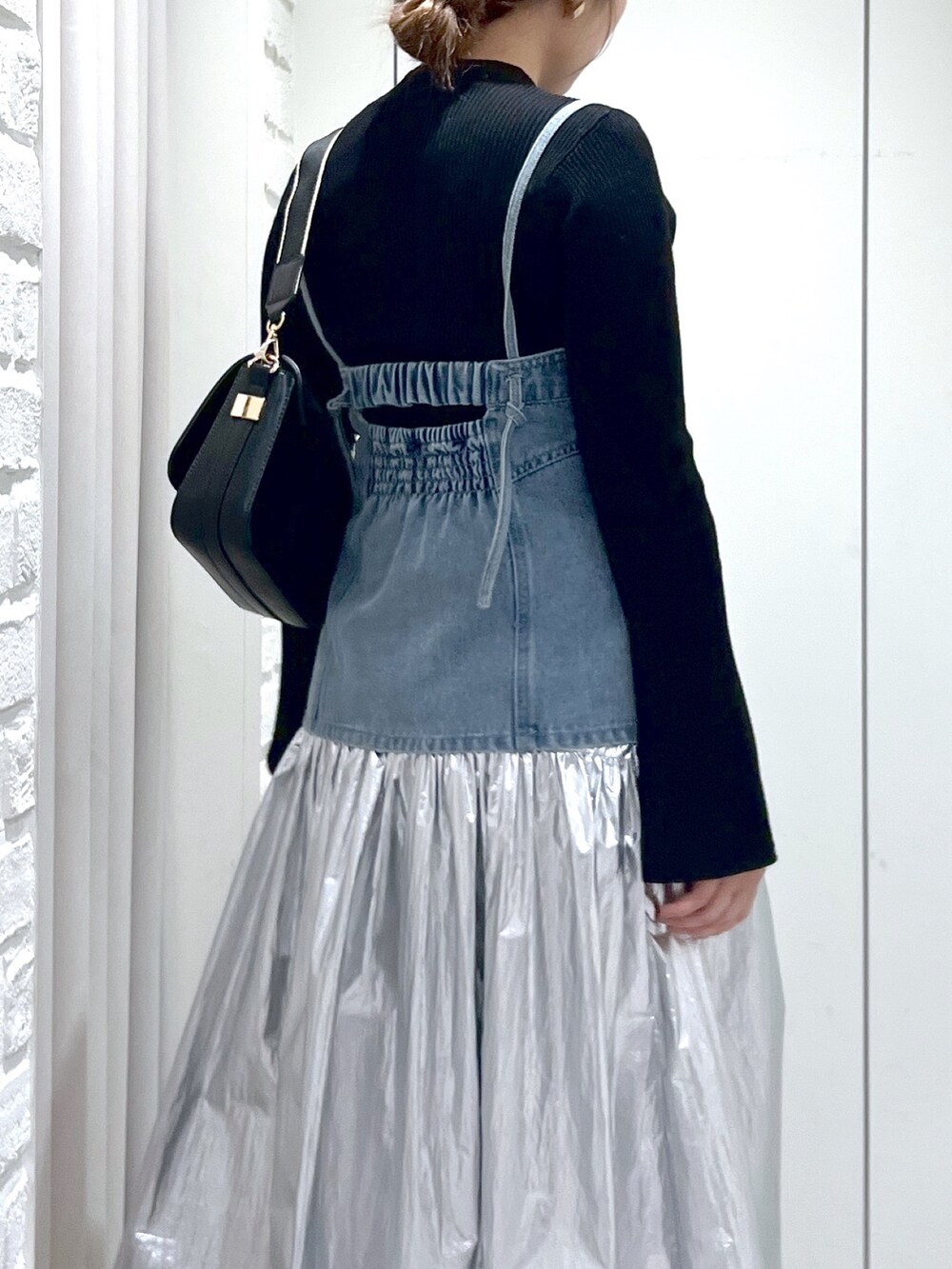 シルバー系のスカート、ブルー系のベスト、ブラック系のニット/セーターを着用したレディースの春コーディネートの6枚目の写真