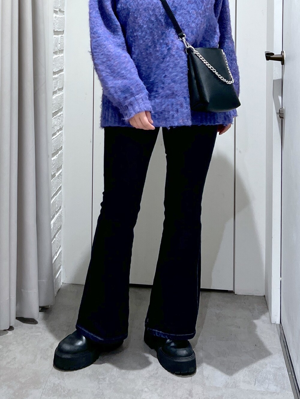 ブルー系のニット/セーター、ブルー系のデニムパンツ、ブラック系のショルダーバッグを着用したレディースの冬コーディネートの4枚目の写真