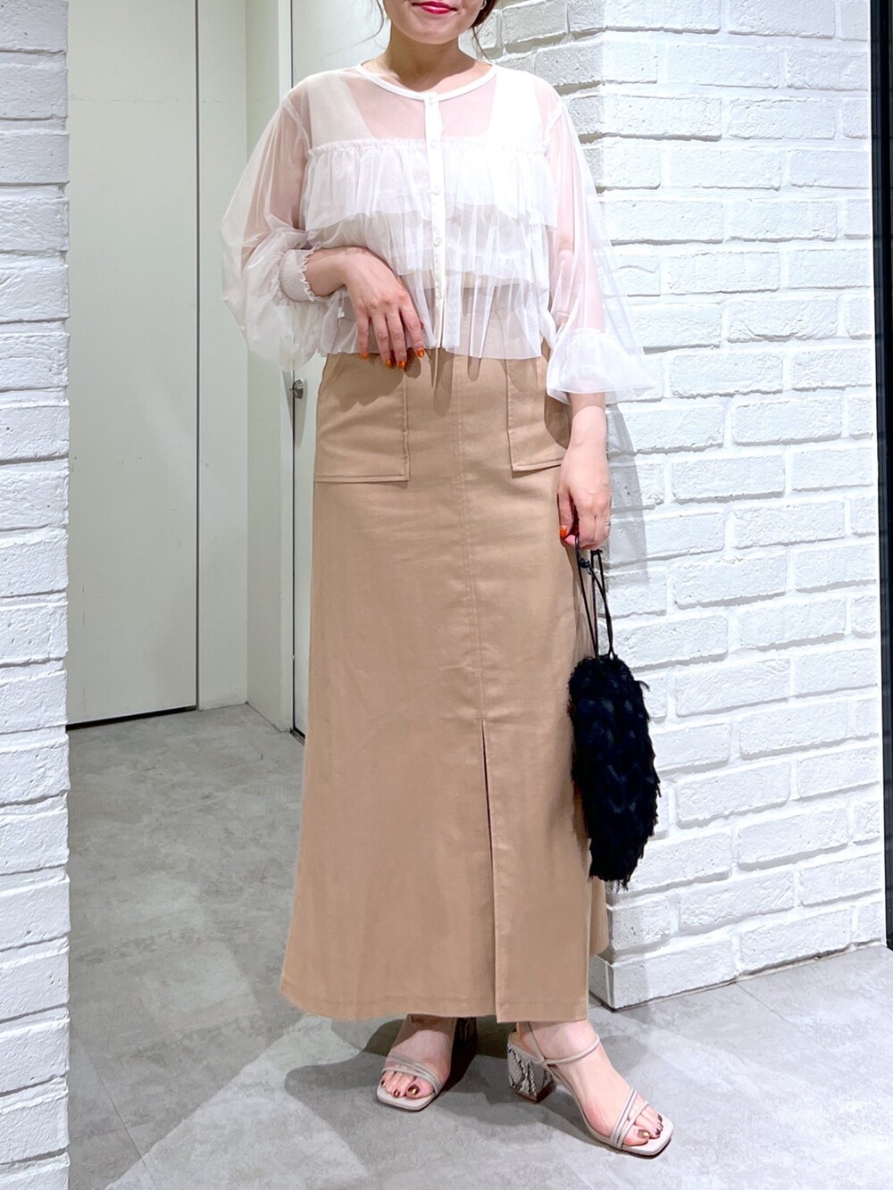 ブラウン系のスカート、ブラック系のハンドバッグ、グレー系のサンダルを着用したレディースの夏コーディネートの6枚目の写真