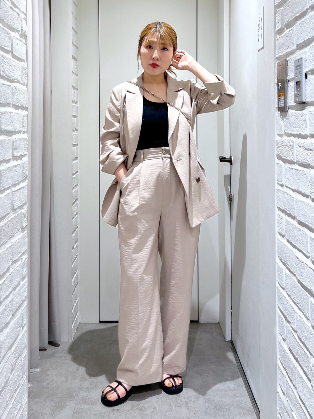 ベージュ系のテーラードジャケット、ベージュ系のスラックス、ブラック系のタンクトップを着用したレディースの夏コーディネートの2枚目の写真