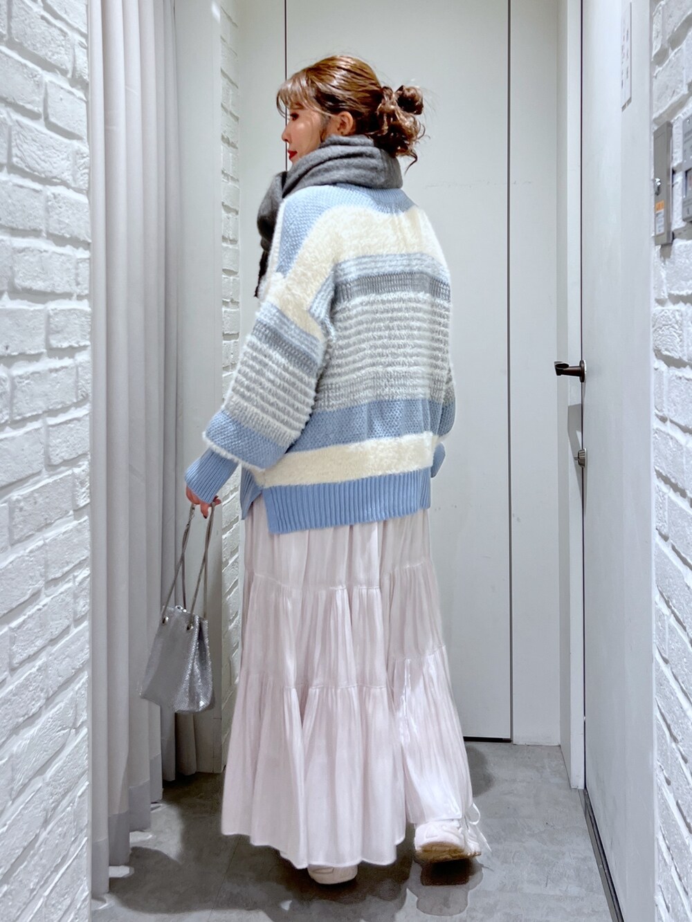 ブルー系のニット/セーター、ホワイト系のスカート、シルバー系のショルダーバッグを着用したレディースの冬コーディネートの3枚目の写真