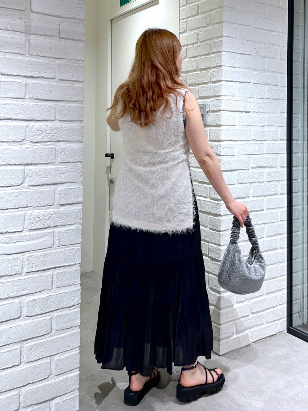 ホワイト系のシャツ/ブラウス、ブラック系のスカート、ブラック系のサンダルを着用したレディースの夏コーディネートの4枚目の写真