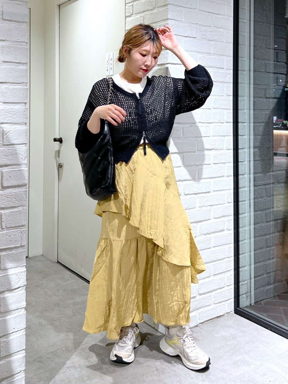 イエロー系のスカート、ブラック系のカーディガン/ボレロ、ホワイト系のTシャツ/カットソーを着用したレディースの夏コーディネートの2枚目の写真