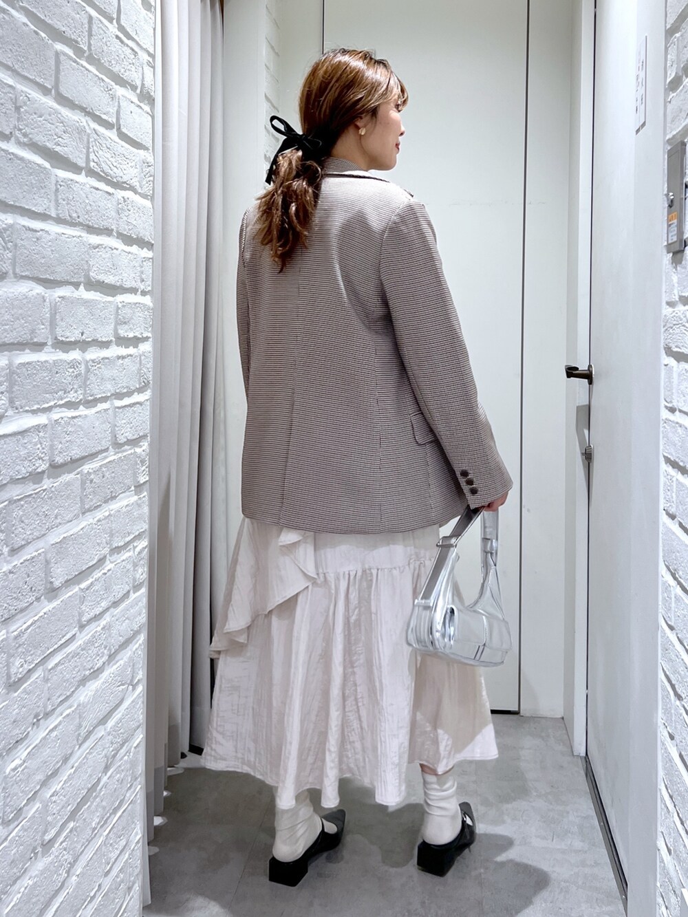 ブラウン系のテーラードジャケット、ホワイト系のスカート、ブラック系のパンプスを着用したレディースの春コーディネートの4枚目の写真