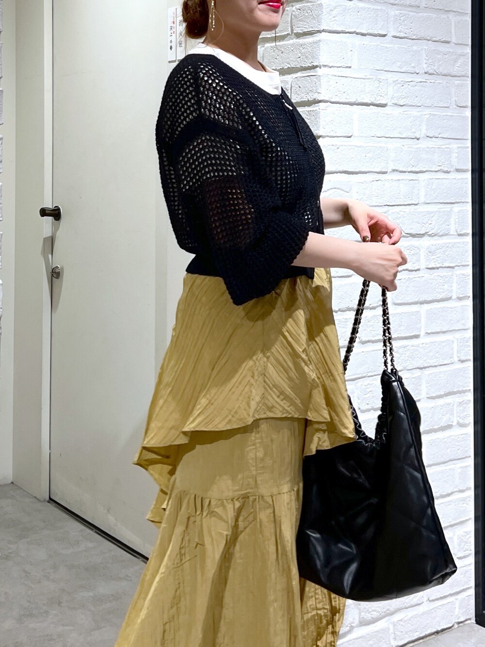 イエロー系のスカート、ブラック系のカーディガン/ボレロ、ホワイト系のTシャツ/カットソーを着用したレディースの夏コーディネートの8枚目の写真