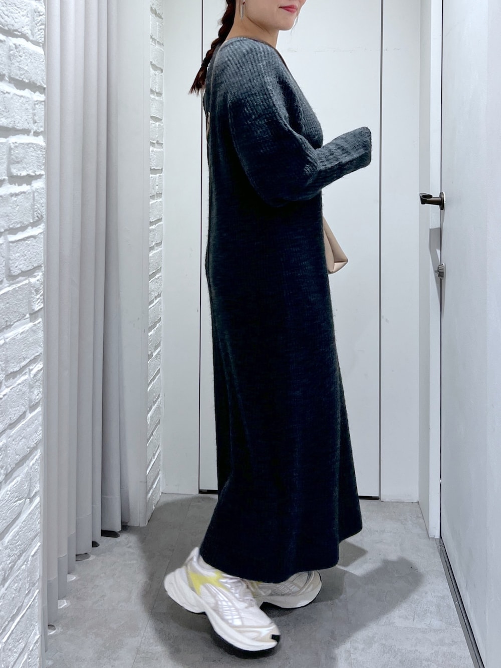 ブラック系のワンピース、ホワイト系のスニーカー、ベージュ系のショルダーバッグを着用したレディースの冬コーディネートの6枚目の写真