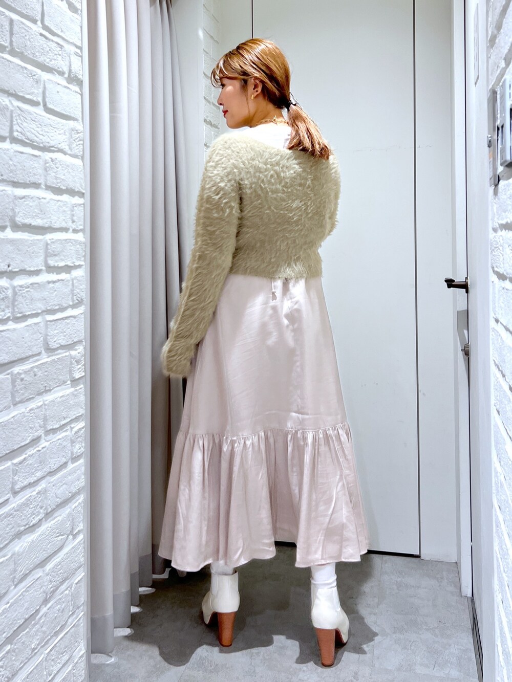 ベージュ系のワンピース、ベージュ系のカーディガン/ボレロ、ホワイト系のブーツを着用したレディースの冬コーディネートの2枚目の写真