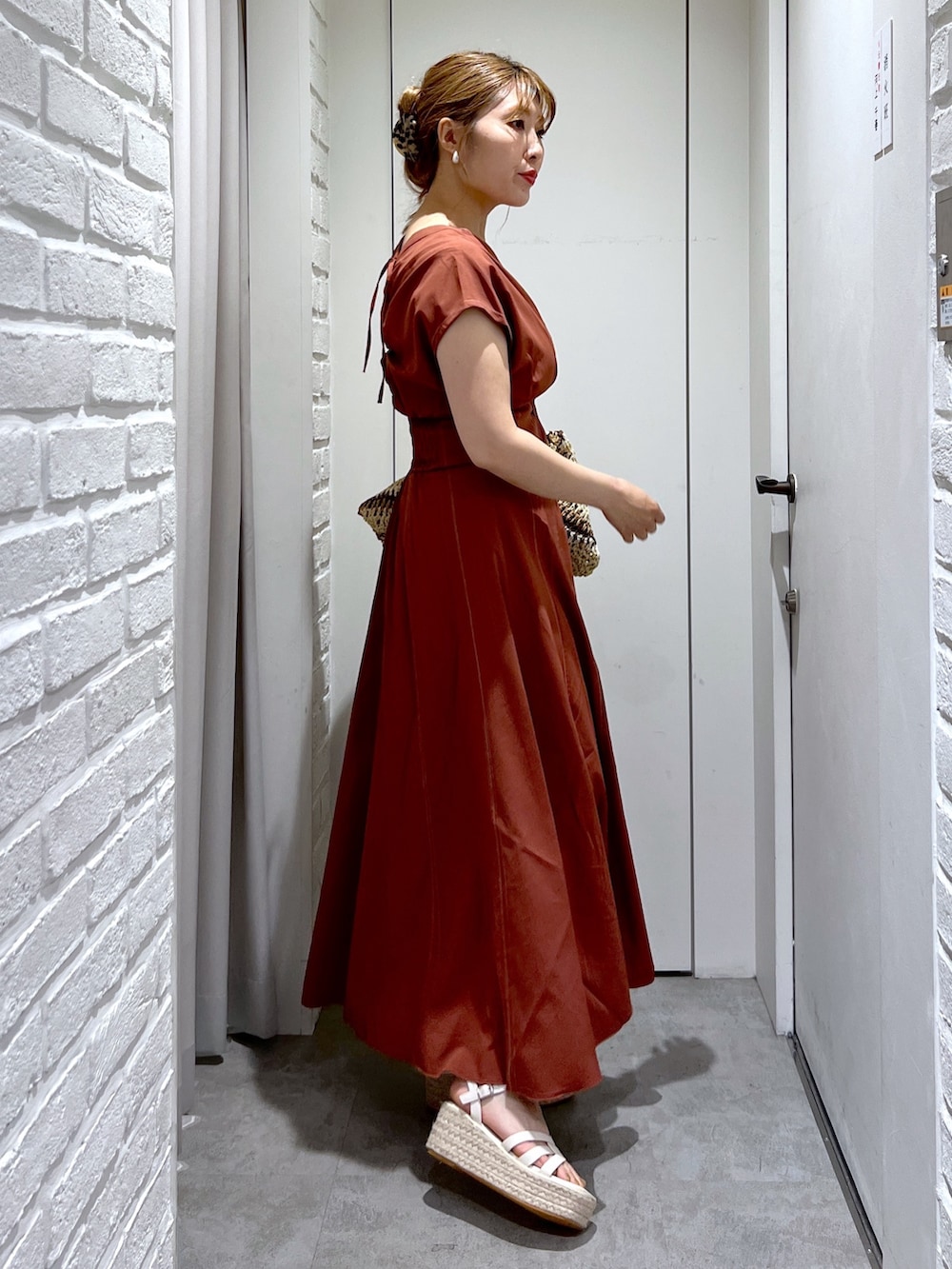 ブラウン系のワンピース、ベージュ系のトートバッグ、ホワイト系のサンダルを着用したレディースの夏コーディネートの3枚目の写真