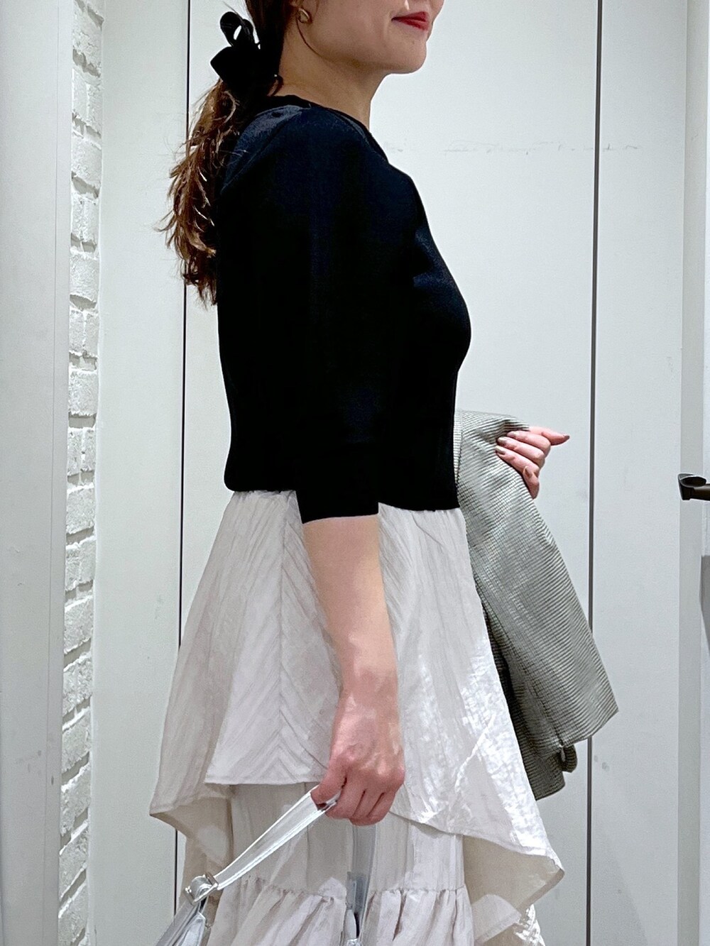 ブラウン系のテーラードジャケット、ホワイト系のスカート、ブラック系のパンプスを着用したレディースの春コーディネートの7枚目の写真