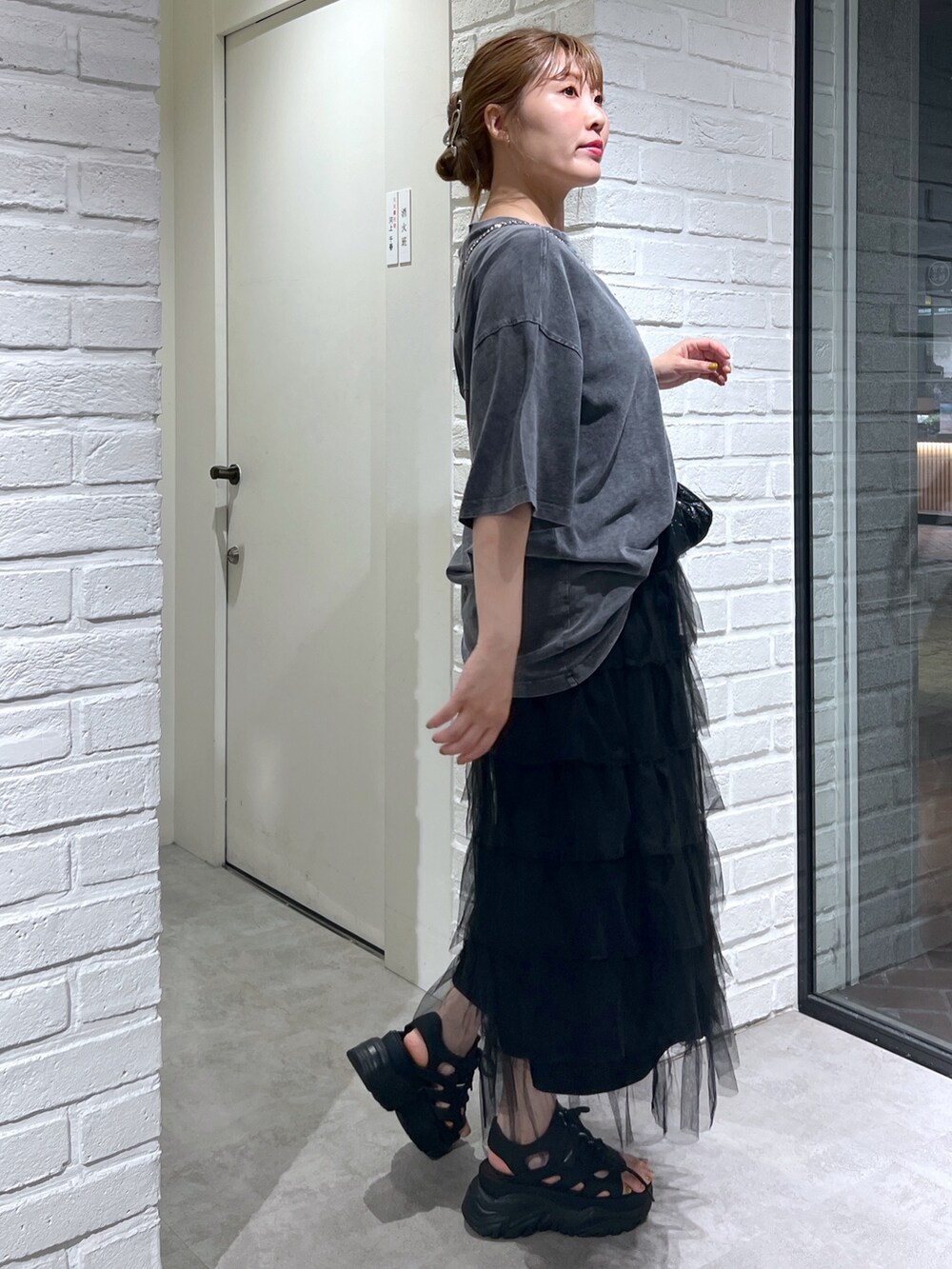 ブラック系のスカート、ブラック系のサンダル、ブラック系のショルダーバッグを着用したレディースの夏コーディネートの3枚目の写真