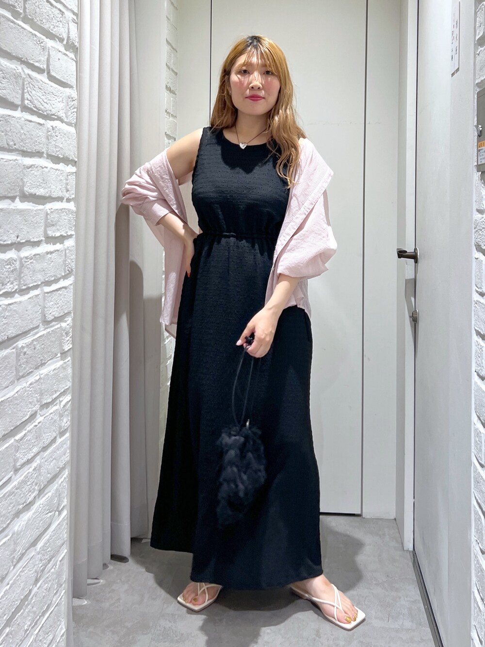 ブラック系のワンピース、ブラック系のハンドバッグ、ホワイト系のサンダルを着用したレディースの夏コーディネートの2枚目の写真