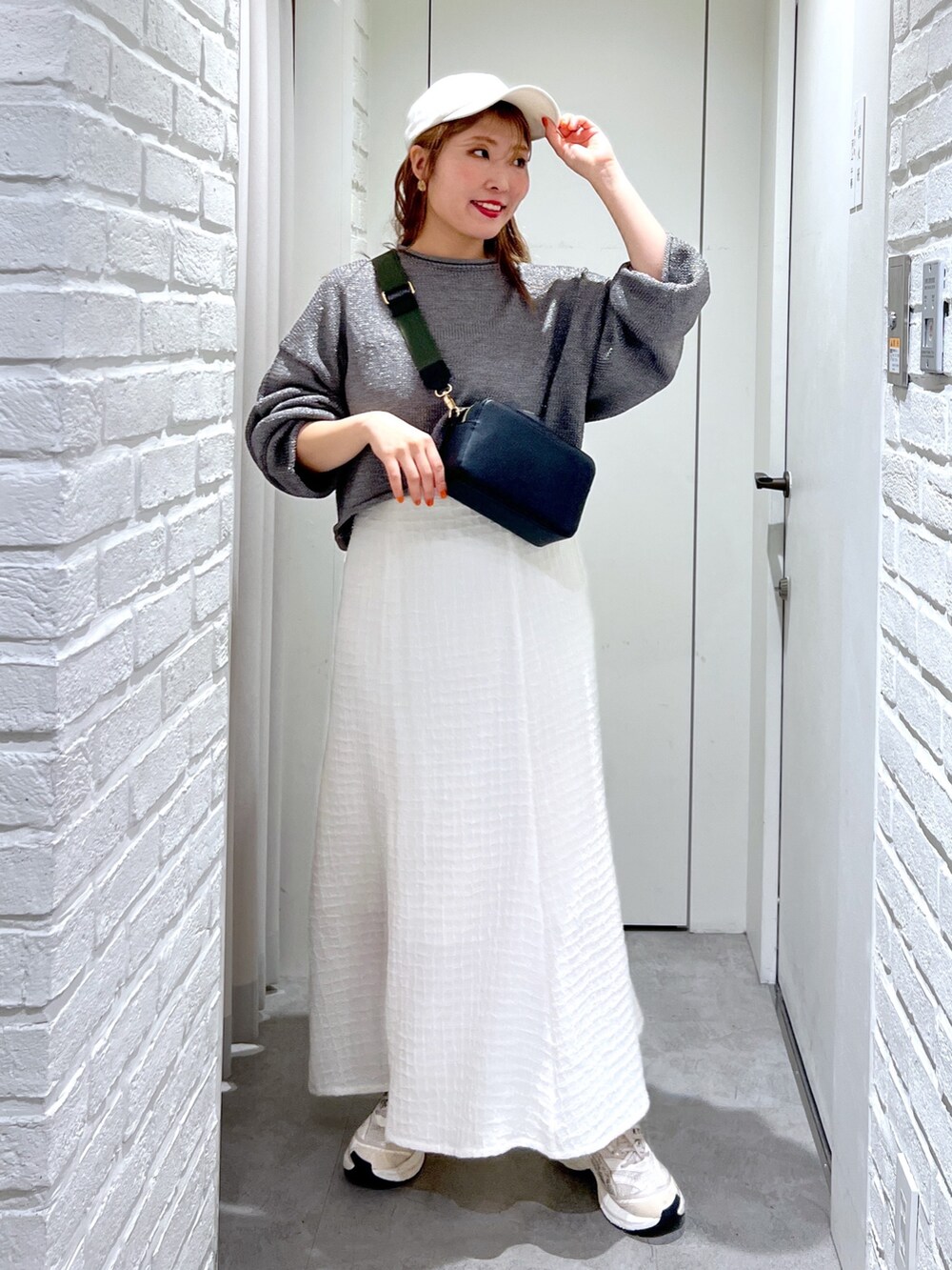 ホワイト系のワンピース、ブラック系のボディバッグ/ウエストポーチ、シルバー系のニット/セーターを着用したレディースの春コーディネートの2枚目の写真