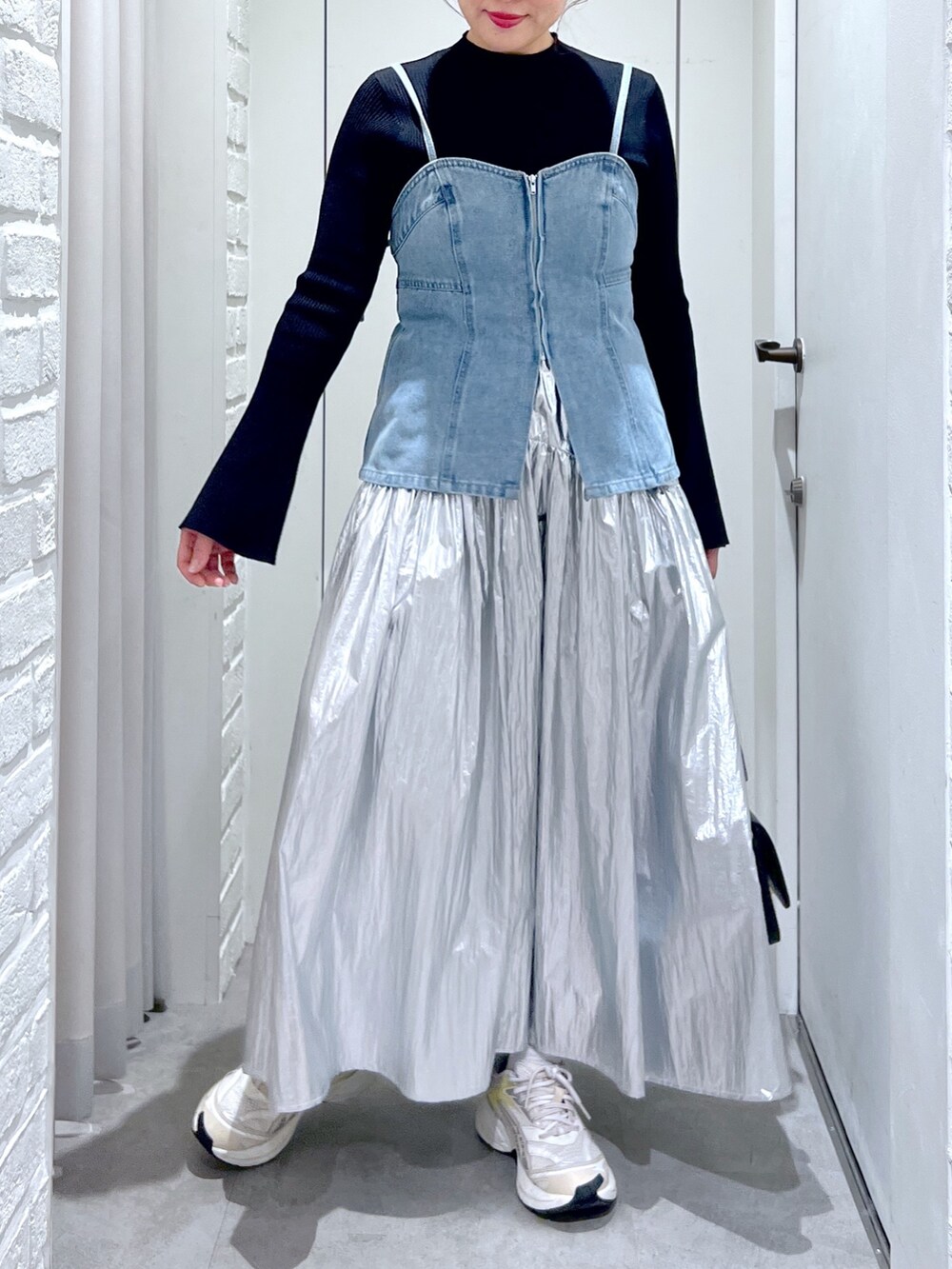 シルバー系のスカート、ブルー系のベスト、ブラック系のニット/セーターを着用したレディースの春コーディネートの5枚目の写真