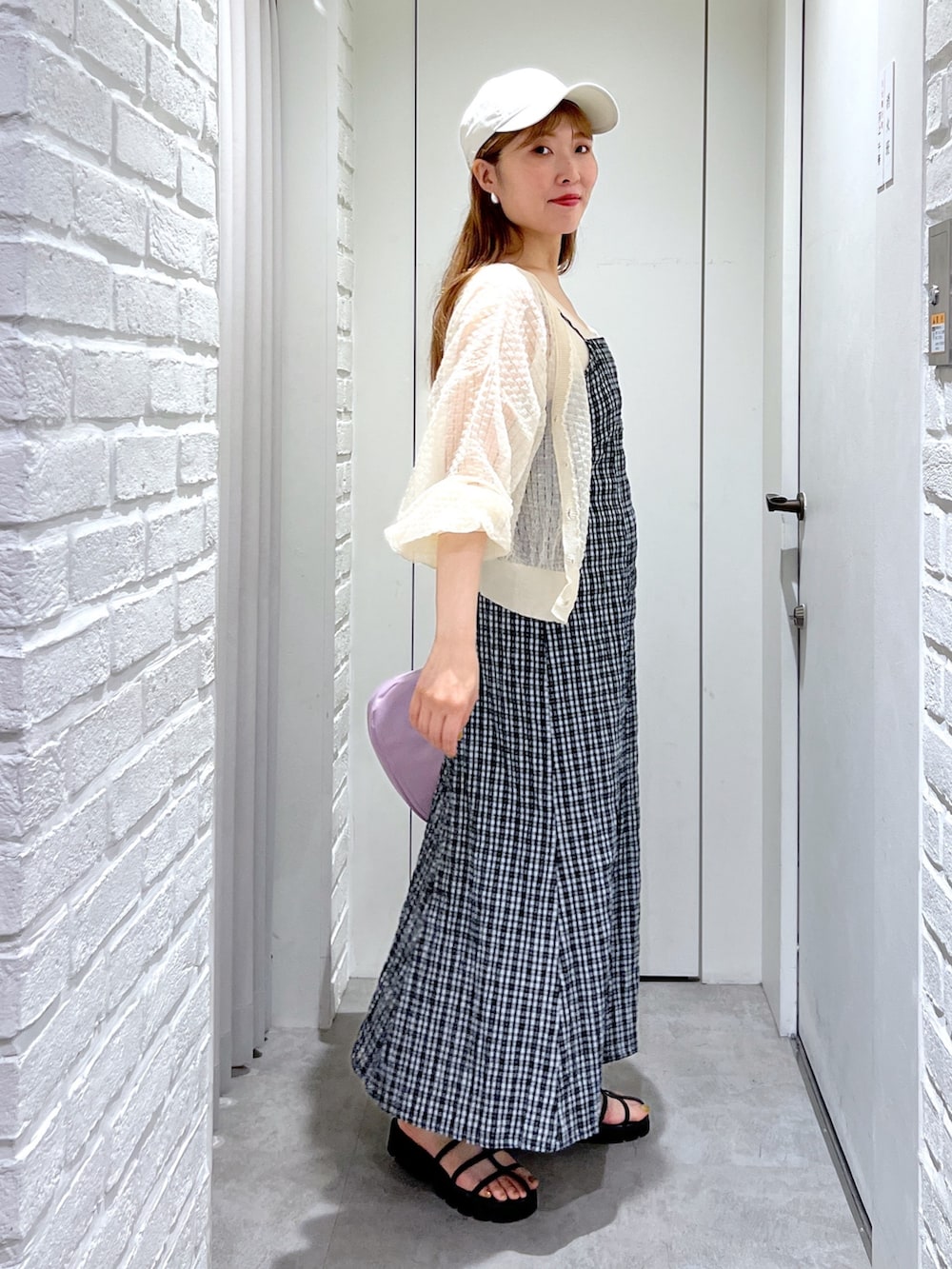 パープル系のハンドバッグ、ブラック系のサンダル、ホワイト系のカーディガン/ボレロを着用したレディースの夏コーディネートの3枚目の写真