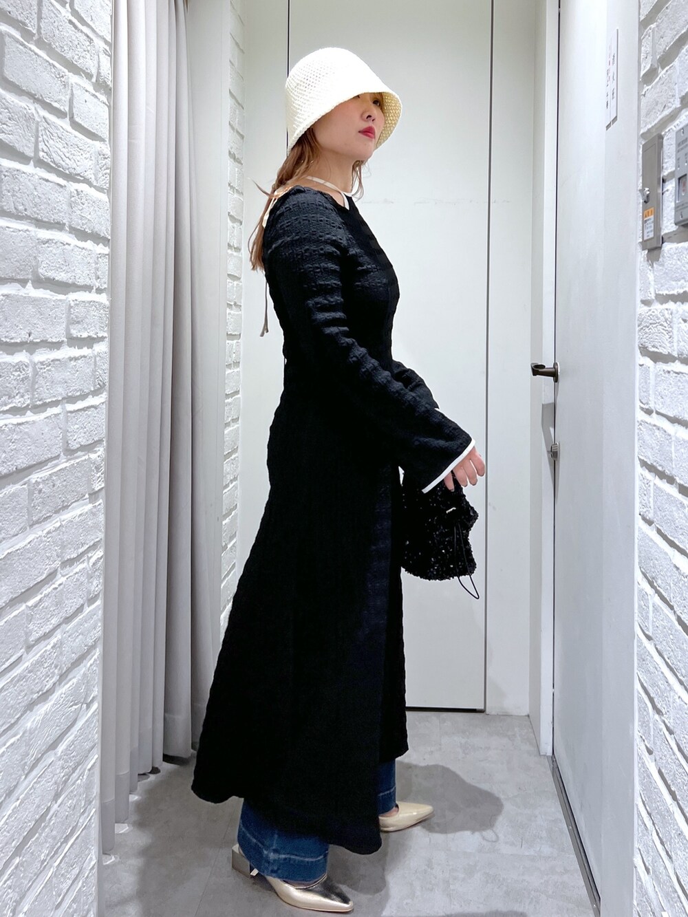 ブラック系のワンピース、ブルー系のデニムパンツ、ブラック系のハンドバッグを着用したレディースの春コーディネートの3枚目の写真