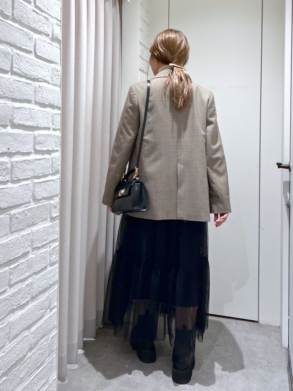 ブラウン系のテーラードジャケット、ホワイト系のニット/セーター、ブラック系のスカートを着用したレディースの秋コーディネートの2枚目の写真