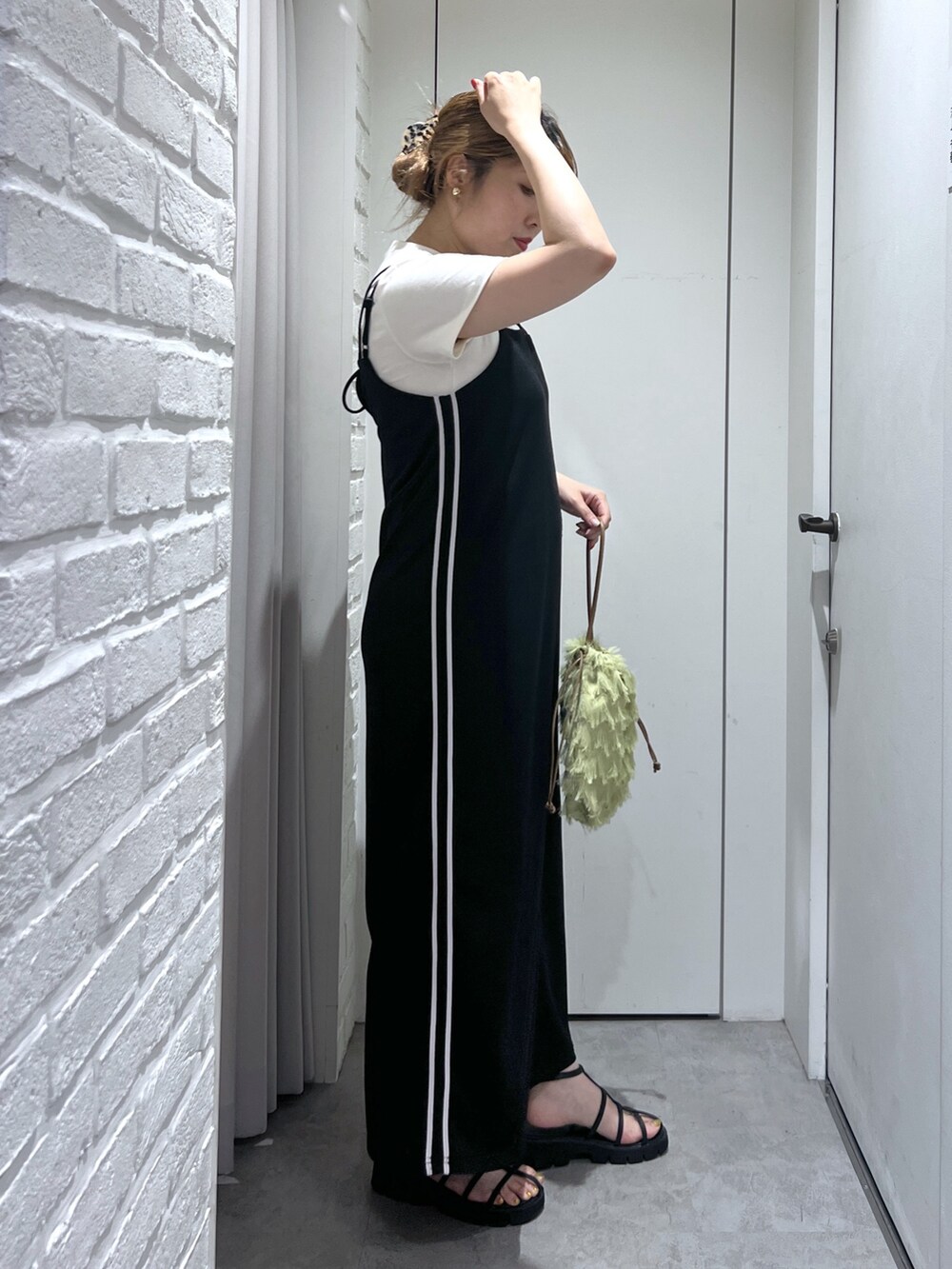 ブラック系のワンピース、ホワイト系のTシャツ/カットソー、ブラック系のサンダルを着用したレディースの夏コーディネートの2枚目の写真