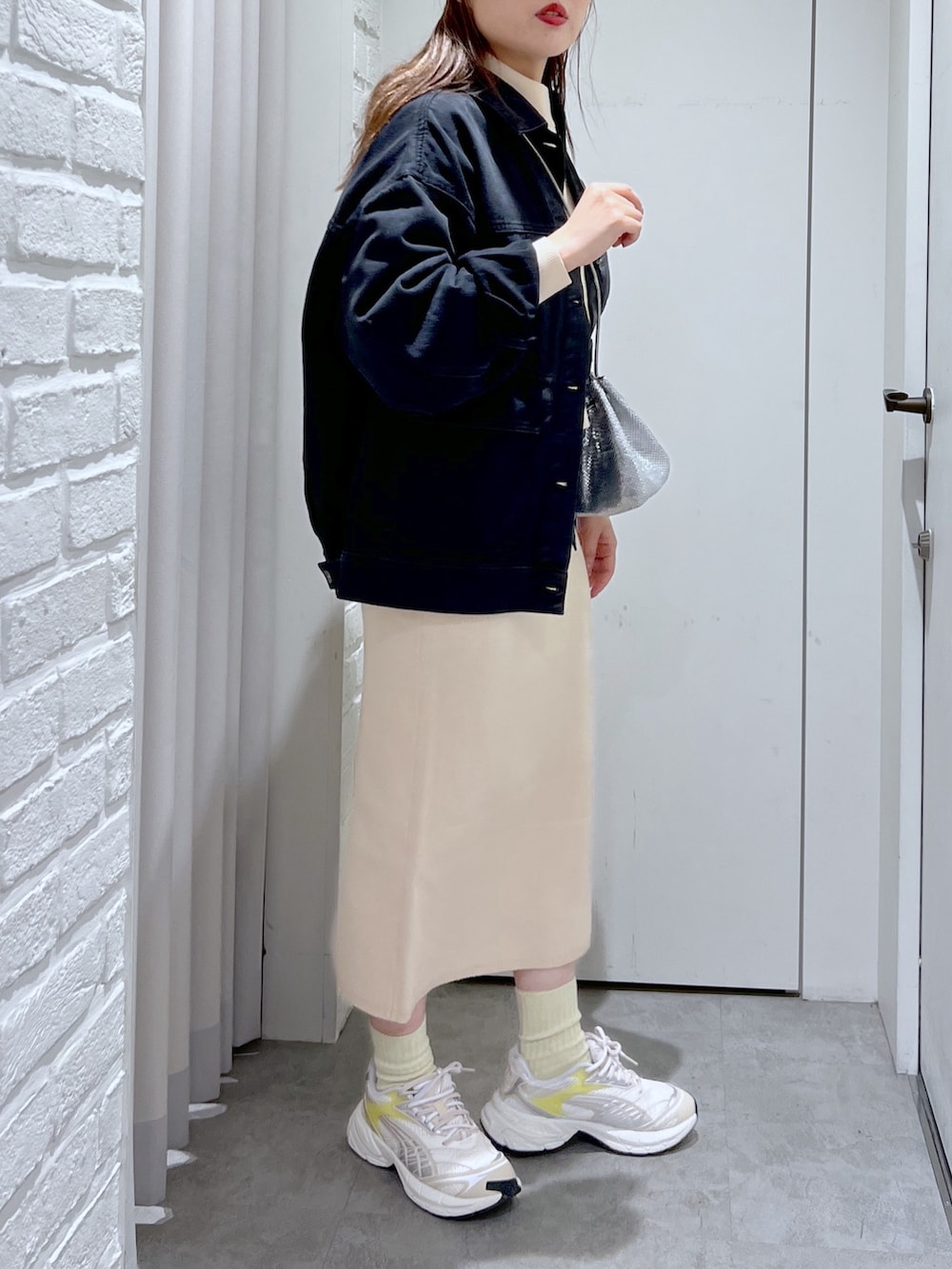 ホワイト系のワンピース、シルバー系のショルダーバッグ、ブラック系のデニムジャケットを着用したレディースの冬コーディネートの5枚目の写真