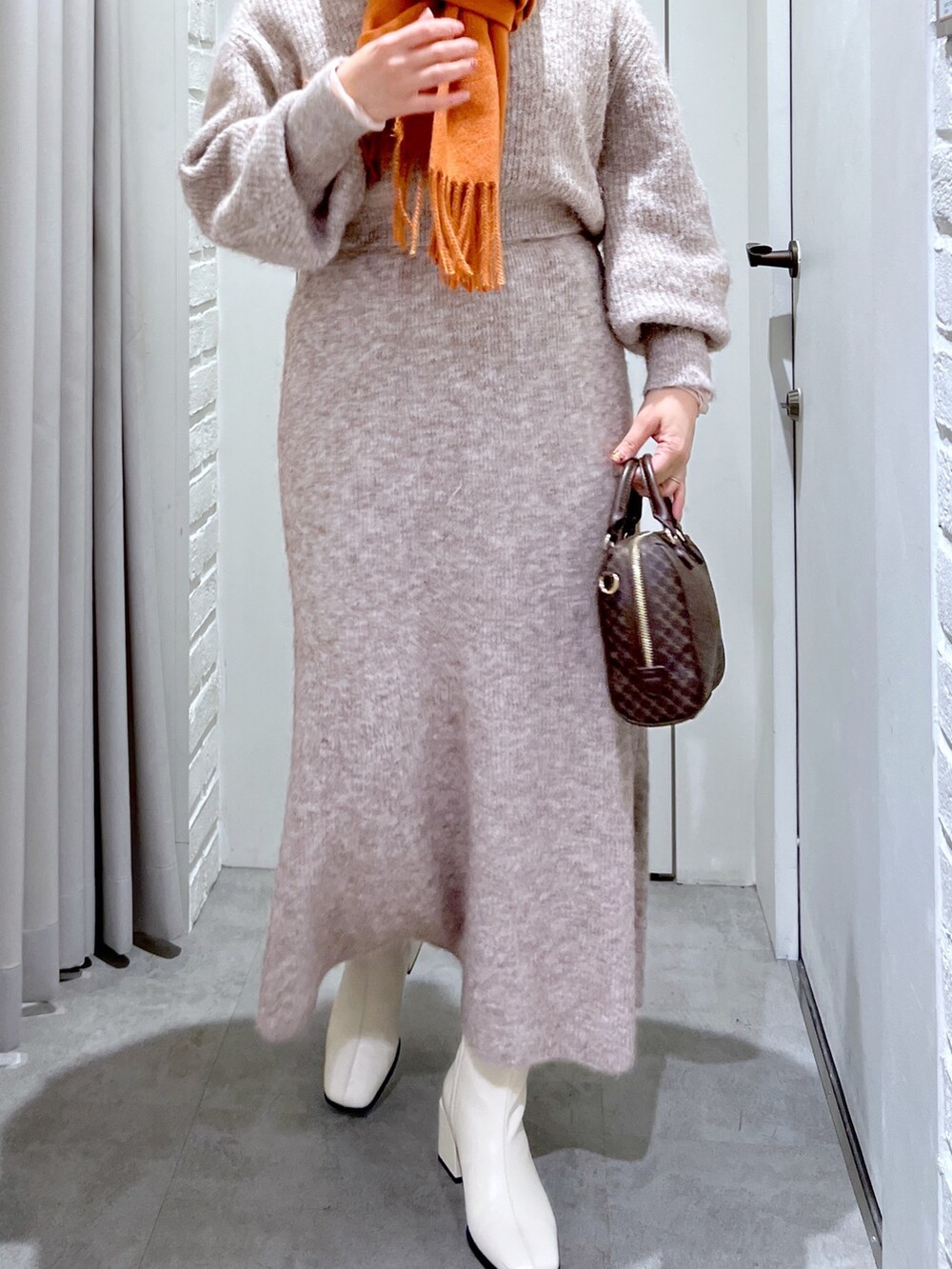 ベージュ系のスカート、ベージュ系のニット/セーター、ベージュ系のバッグを着用したレディースの冬コーディネートの6枚目の写真