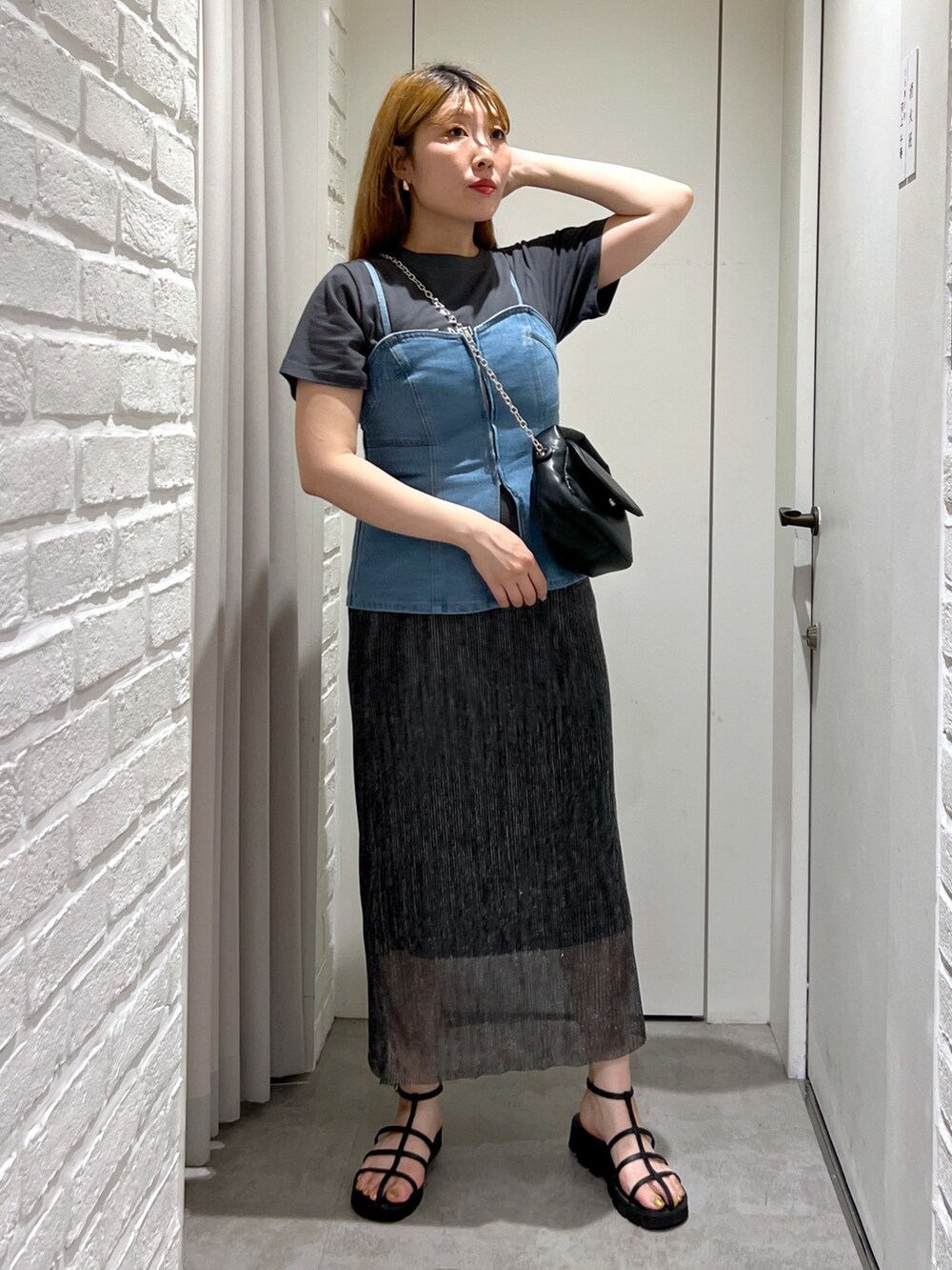 ブラック系のスカート、ブルー系のベスト、ブラック系のショルダーバッグを着用したレディースの夏コーディネートの2枚目の写真