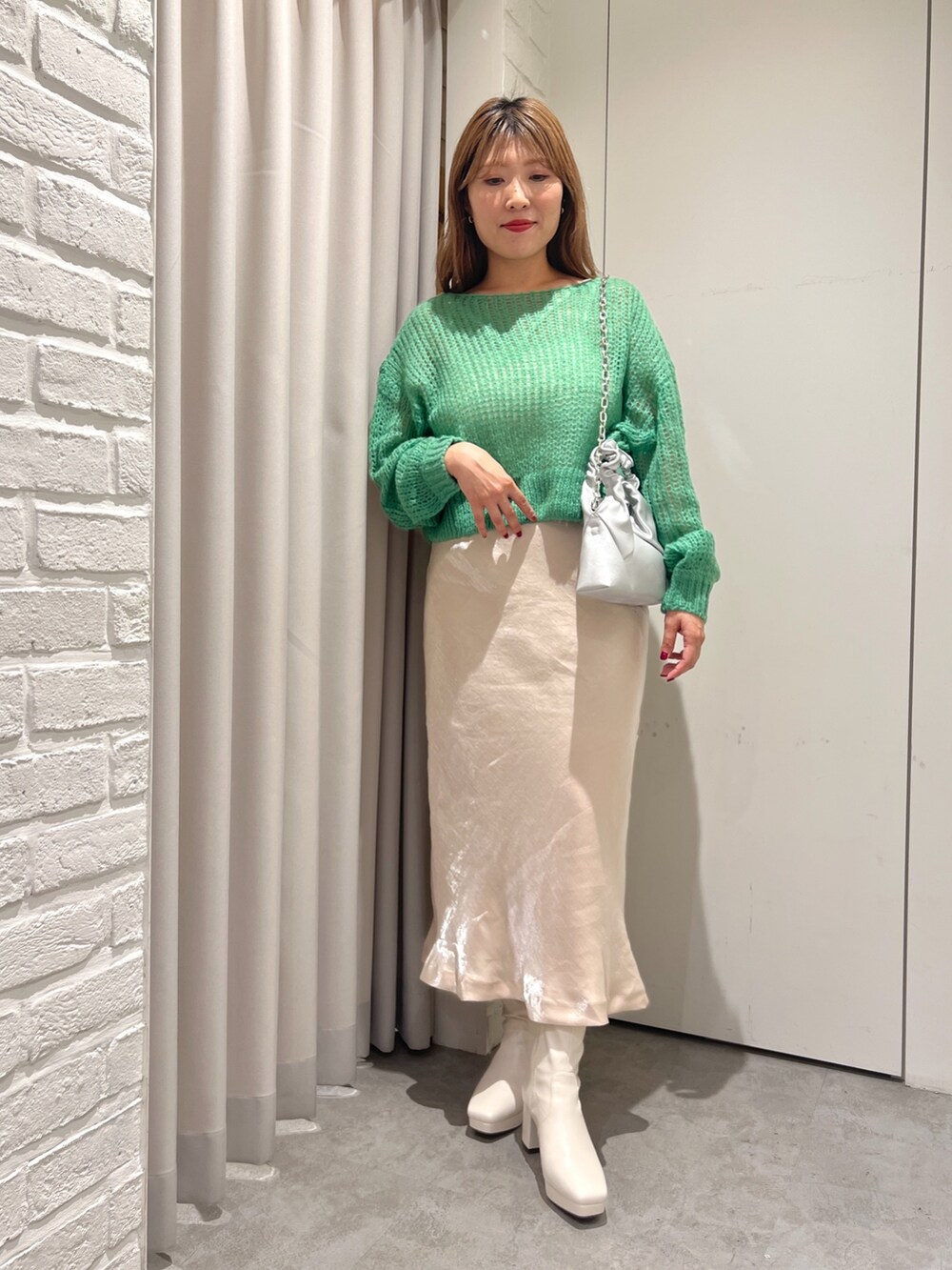 グリーン系のニット/セーター、ベージュ系のスカート、ホワイト系のブーツを着用したレディースの秋コーディネートの2枚目の写真