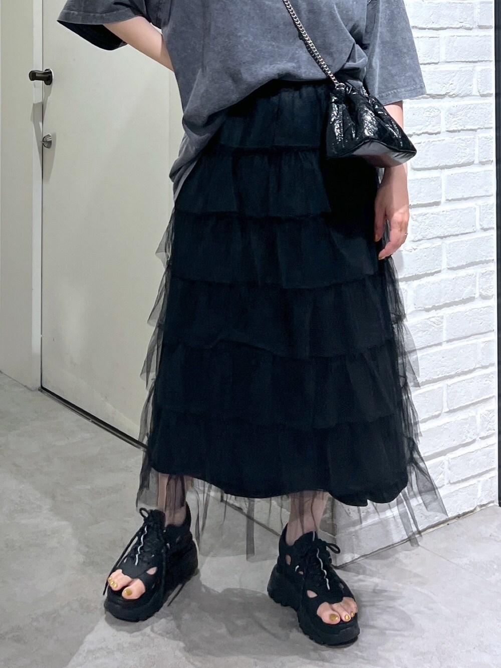 ブラック系のスカート、ブラック系のサンダル、ブラック系のショルダーバッグを着用したレディースの夏コーディネートの6枚目の写真