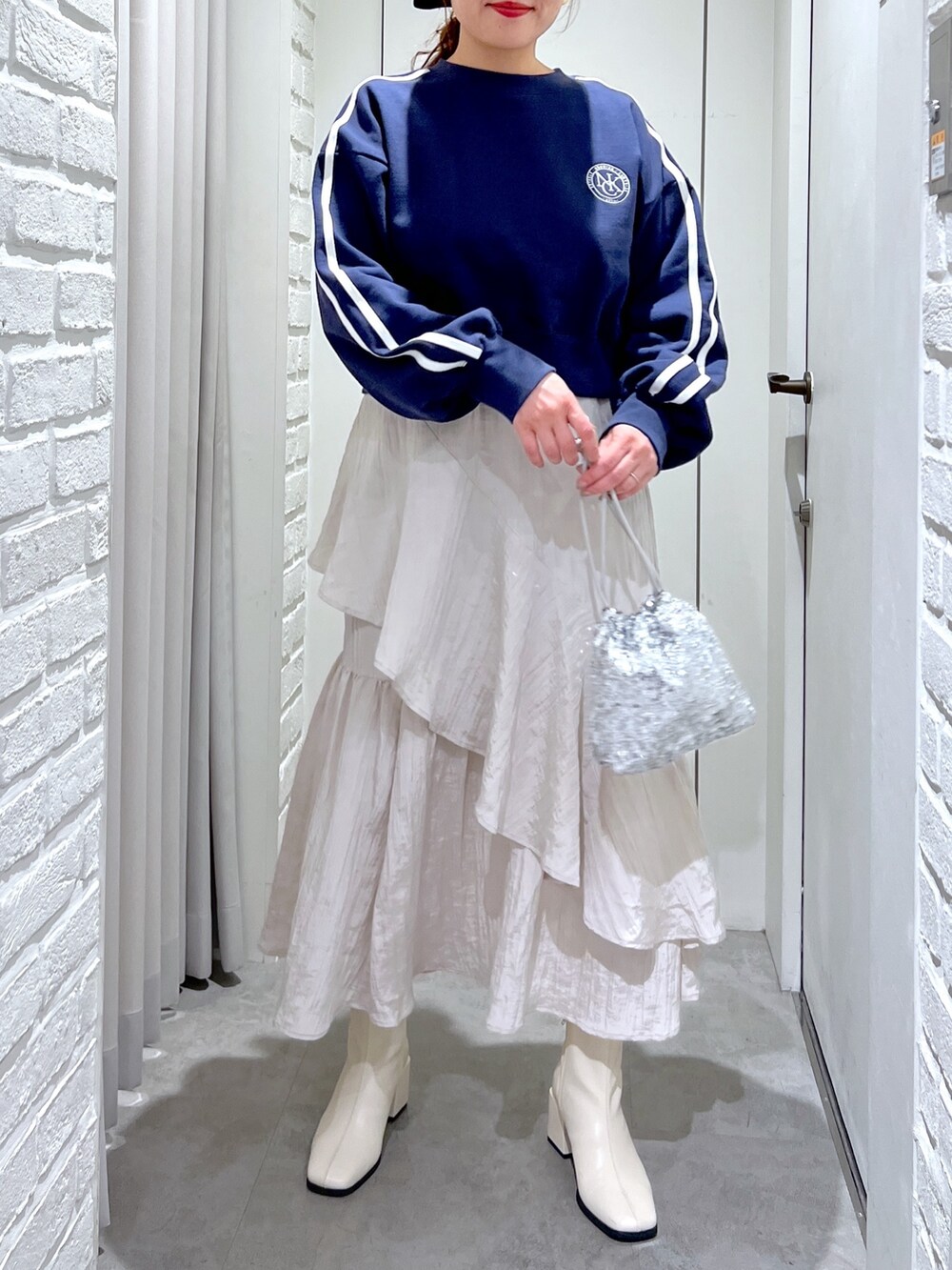 ホワイト系のスカート、ホワイト系のブーツ、シルバー系のハンドバッグを着用したレディースの春コーディネートの4枚目の写真