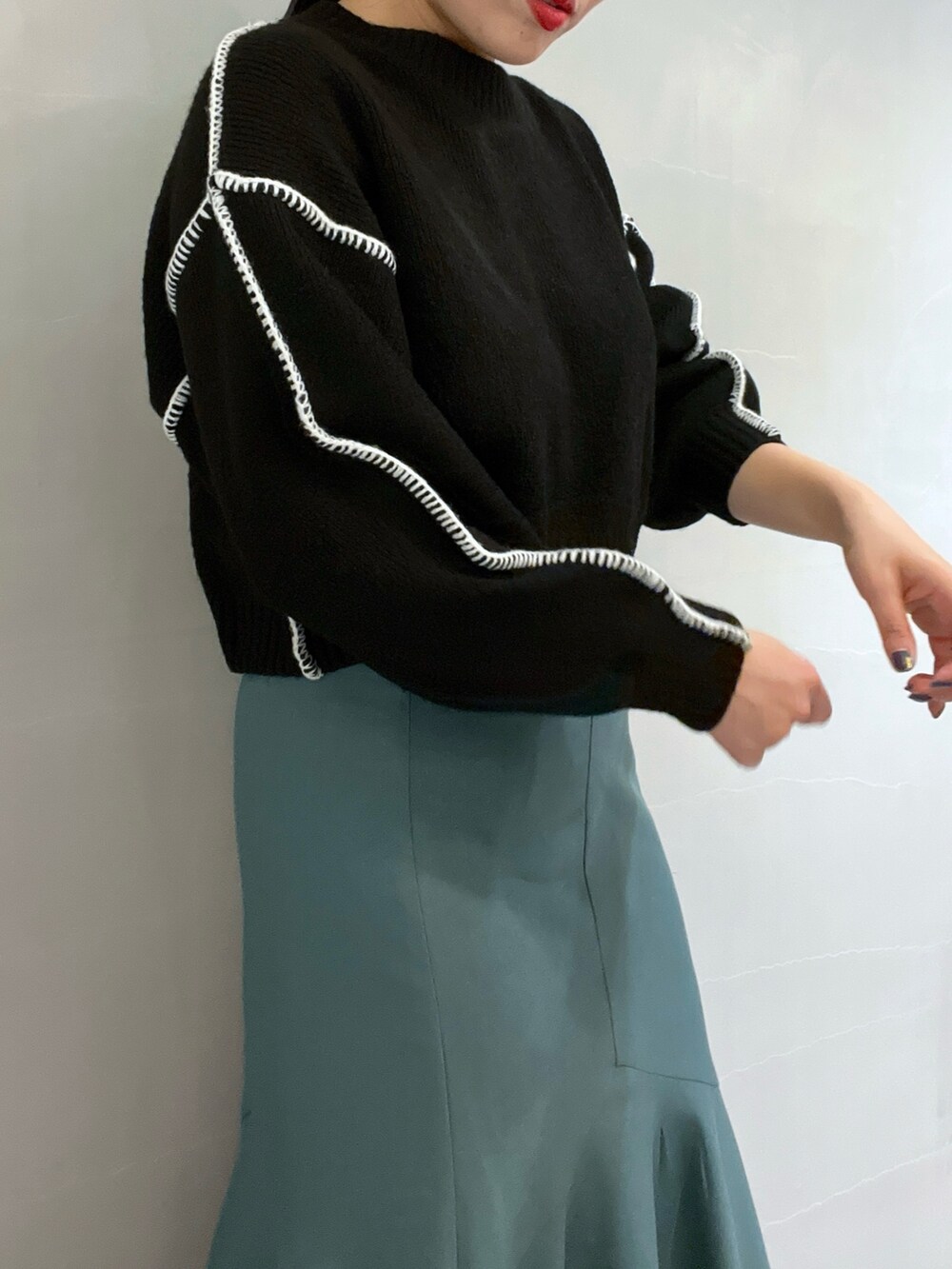 グリーン系のスカート、ブラック系のニット/セーター、ホワイト系のショルダーバッグを着用したレディースの冬コーディネートの6枚目の写真