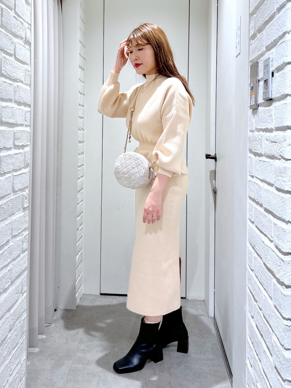 ホワイト系のワンピース、ブラック系のブーツ、ベージュ系のショルダーバッグを着用したレディースの冬コーディネートの2枚目の写真