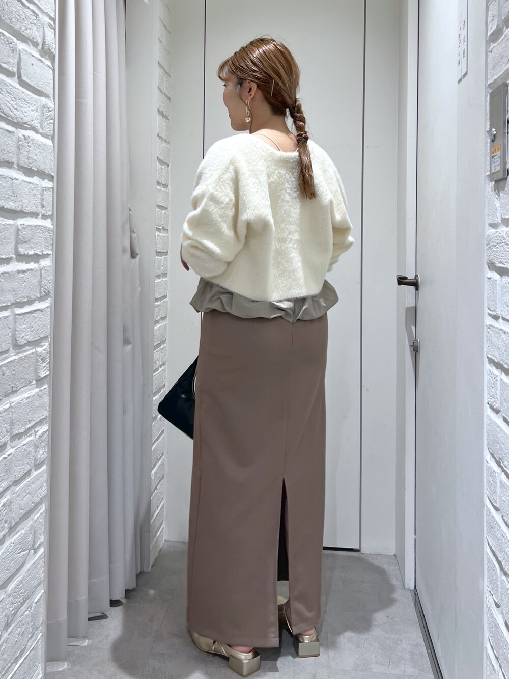 ブラウン系のワンピース、ブラック系のショルダーバッグ、ゴールド系のパンプスを着用したレディースの冬コーディネートの4枚目の写真