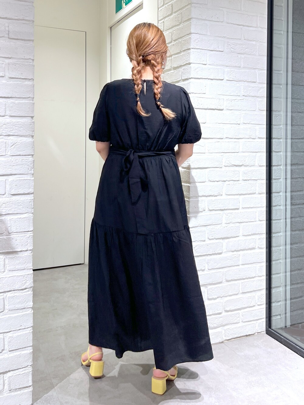 ホワイト系のショルダーバッグ、ブラック系のワンピース、イエロー系のサンダルを着用したレディースの夏コーディネートの4枚目の写真