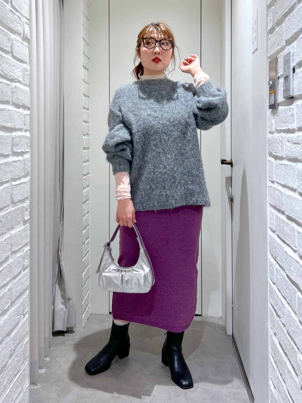 パープル系のスカート、グレー系のニット/セーター、ブラック系のブーツを着用したレディースの冬コーディネートの2枚目の写真