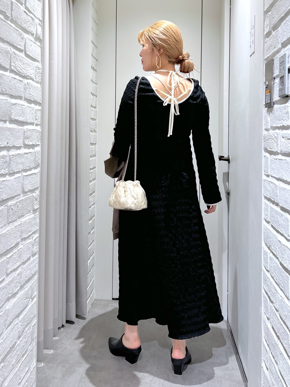 ブラック系のワンピース、ブラック系のパンプス、ゴールド系のショルダーバッグを着用したレディースの春コーディネートの6枚目の写真