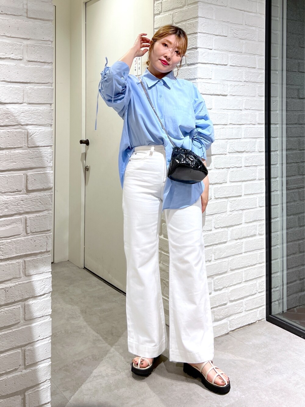 ブルー系のシャツ/ブラウス、ブラック系のショルダーバッグ、ホワイト系のデニムパンツを着用したレディースの夏コーディネートの2枚目の写真