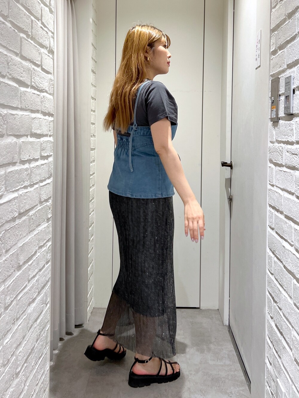 ブラック系のスカート、ブルー系のベスト、ブラック系のショルダーバッグを着用したレディースの夏コーディネートの3枚目の写真