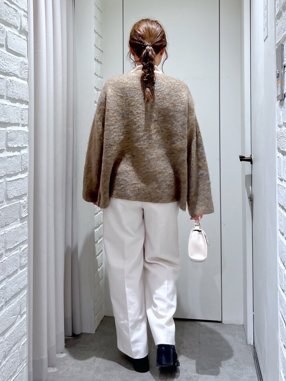 ベージュ系のニット/セーター、ホワイト系のスラックス、ホワイト系のショルダーバッグを着用したレディースの冬コーディネートの2枚目の写真