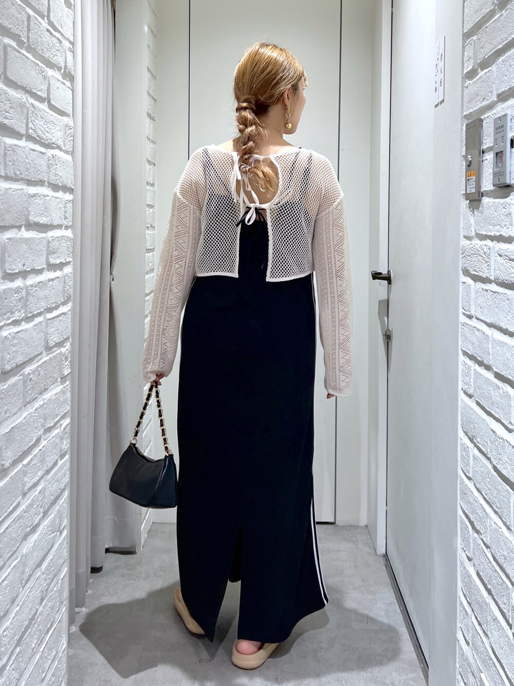 ブラック系のワンピース、ホワイト系のカーディガン/ボレロ、ブラック系のトートバッグを着用したレディースの夏コーディネートの4枚目の写真