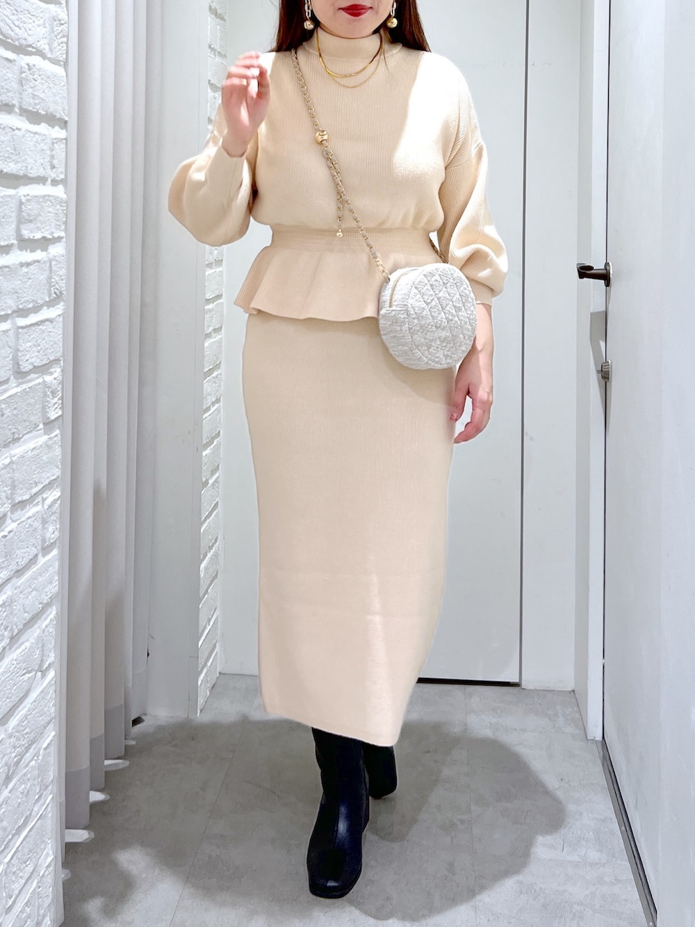 ホワイト系のワンピース、ブラック系のブーツ、ベージュ系のショルダーバッグを着用したレディースの冬コーディネートの5枚目の写真