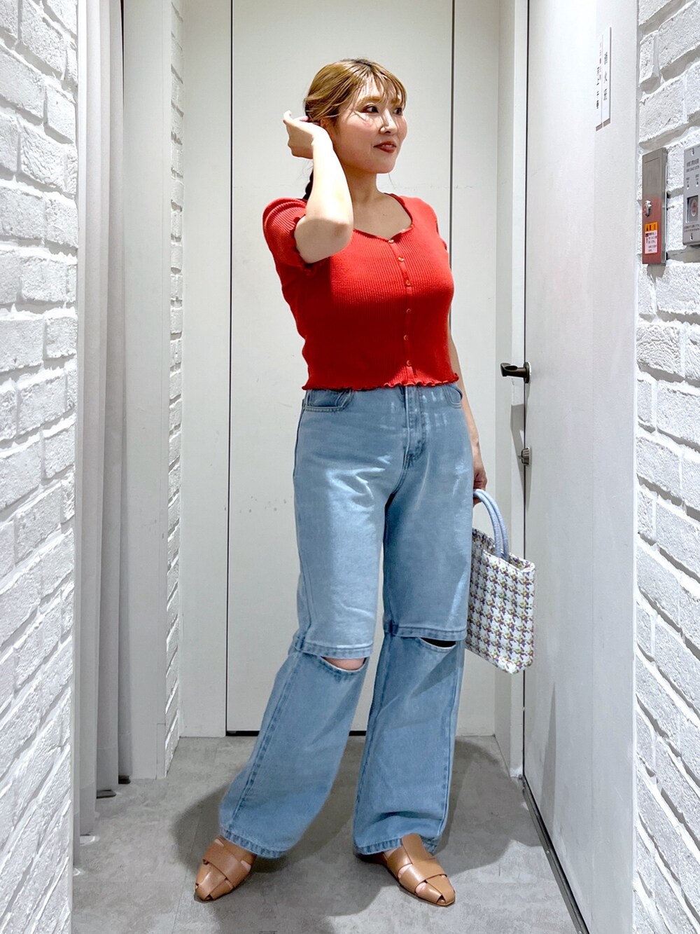 レッド系のニット/セーター、ブルー系のデニムパンツ、ベージュ系のスリッポンを着用したレディースの夏コーディネートの4枚目の写真