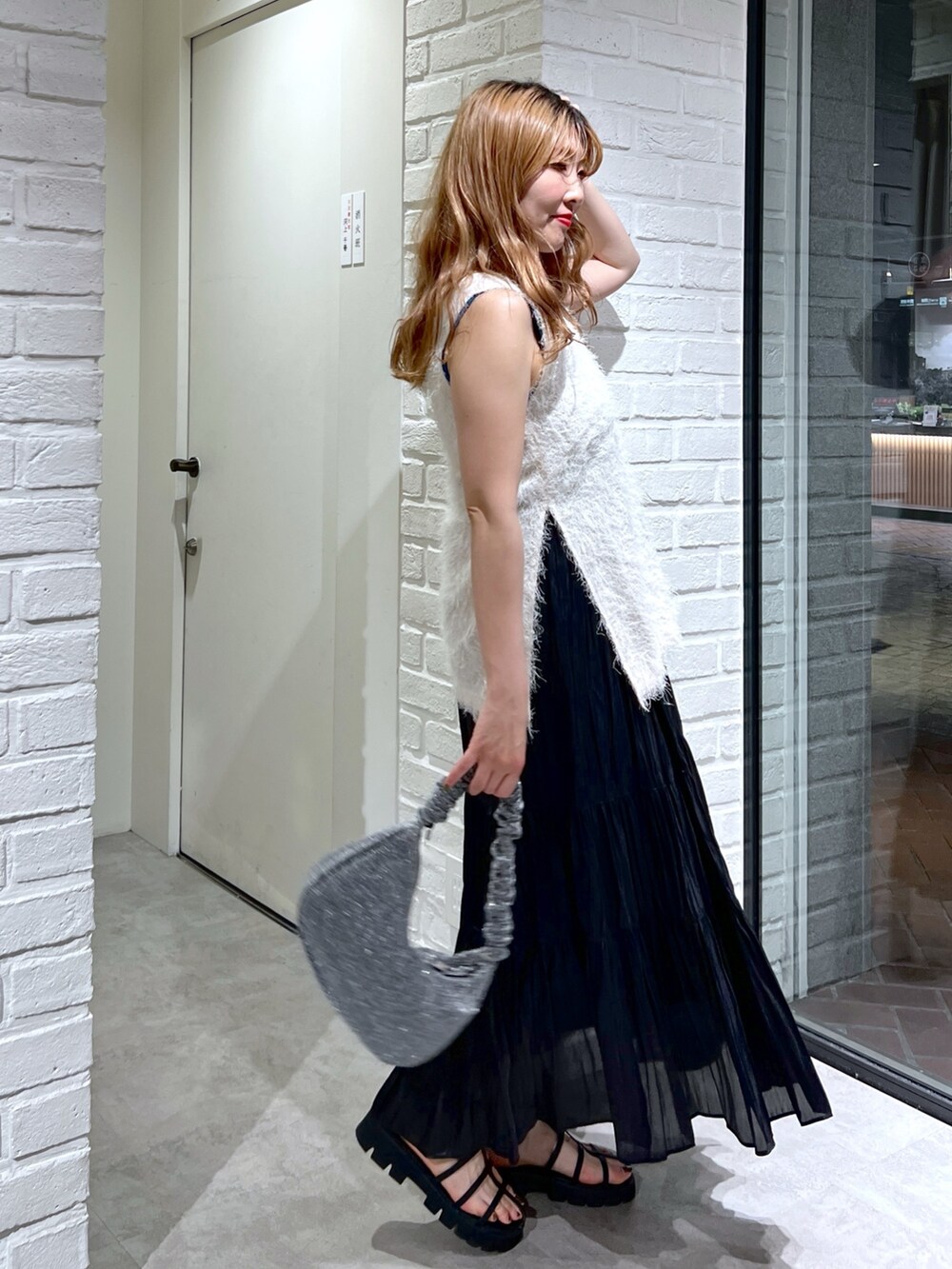 ホワイト系のシャツ/ブラウス、ブラック系のスカート、ブラック系のサンダルを着用したレディースの夏コーディネートの3枚目の写真