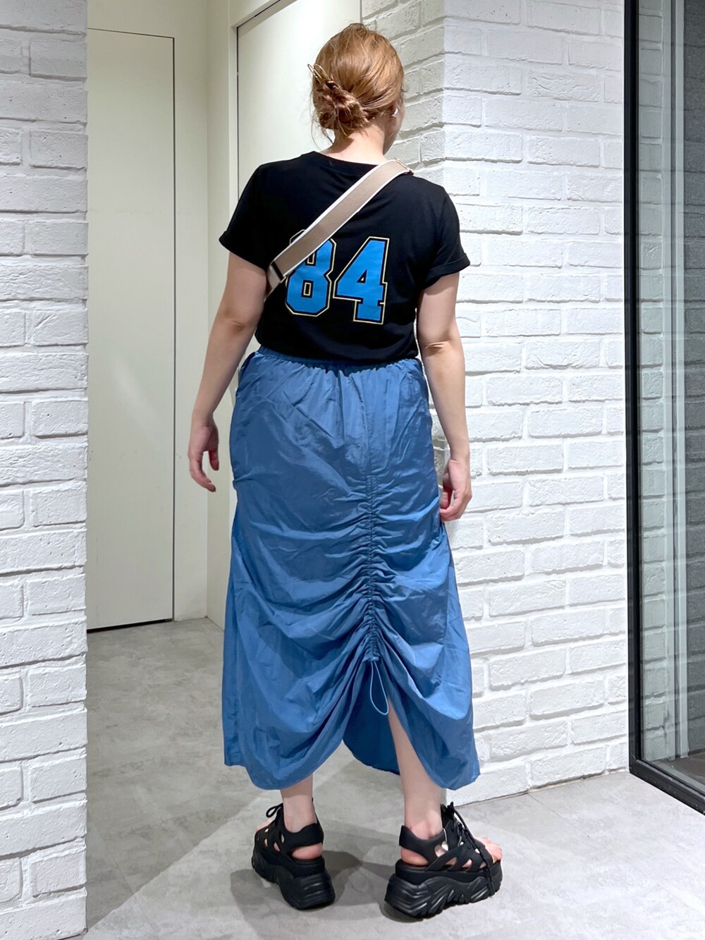 ブルー系のスカート、ブラック系のTシャツ/カットソー、ブラック系のサンダルを着用したレディースの夏コーディネートの4枚目の写真