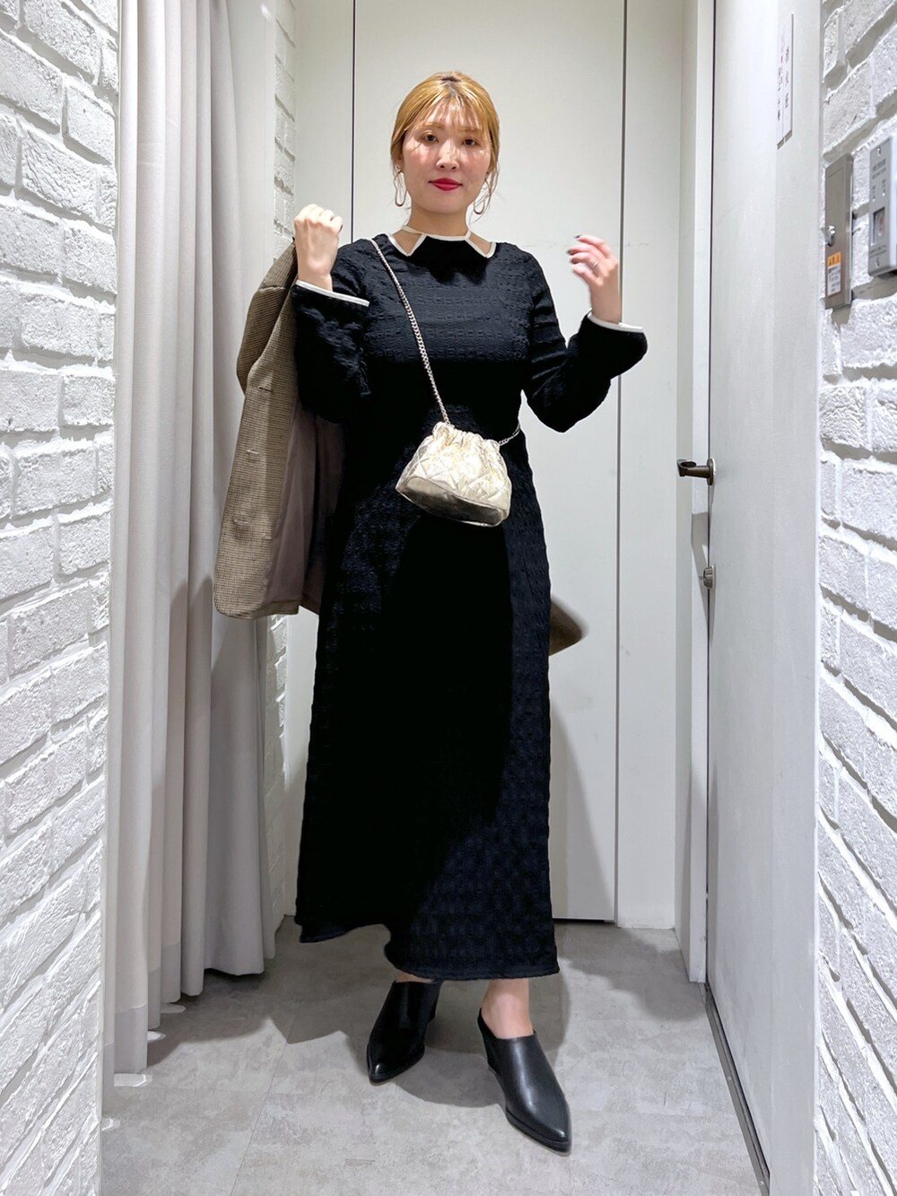 ブラック系のワンピース、ブラック系のパンプス、ゴールド系のショルダーバッグを着用したレディースの春コーディネートの4枚目の写真