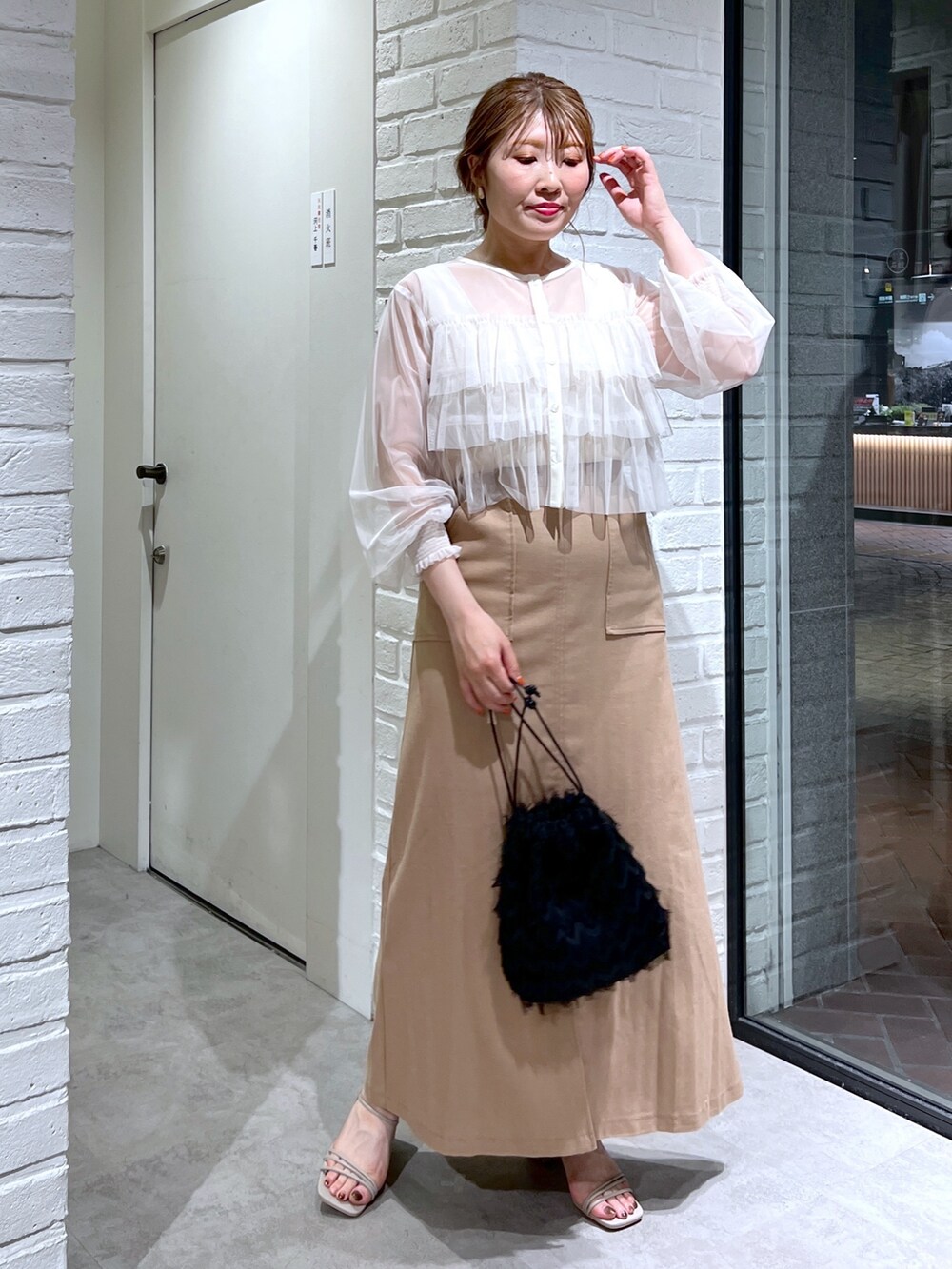 ブラウン系のスカート、ブラック系のハンドバッグ、グレー系のサンダルを着用したレディースの夏コーディネートの2枚目の写真