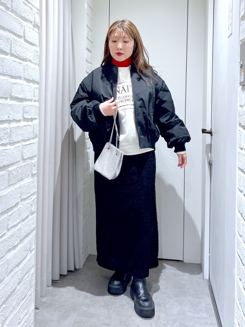 ブラック系のスカート、ホワイト系のスウェット、ブラック系のMA-1を着用したレディースの冬コーディネートの2枚目の写真