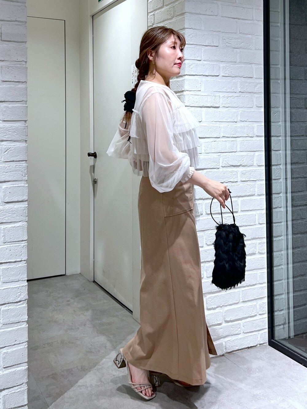 ブラウン系のスカート、ブラック系のハンドバッグ、グレー系のサンダルを着用したレディースの夏コーディネートの3枚目の写真